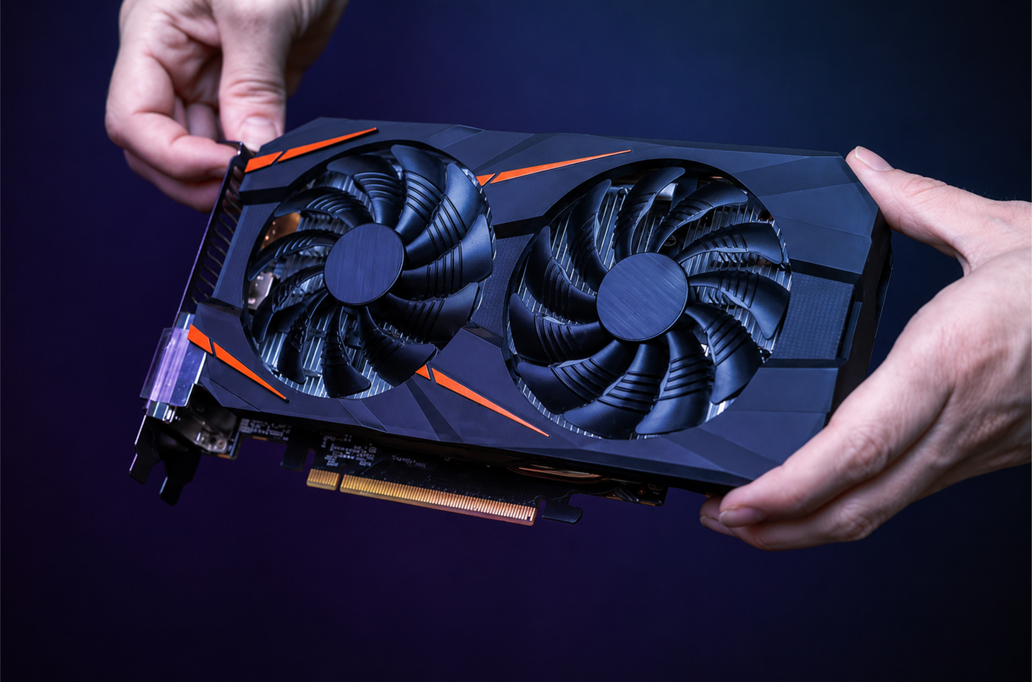 Hands holding a black dual-fan graphics card against a dark background